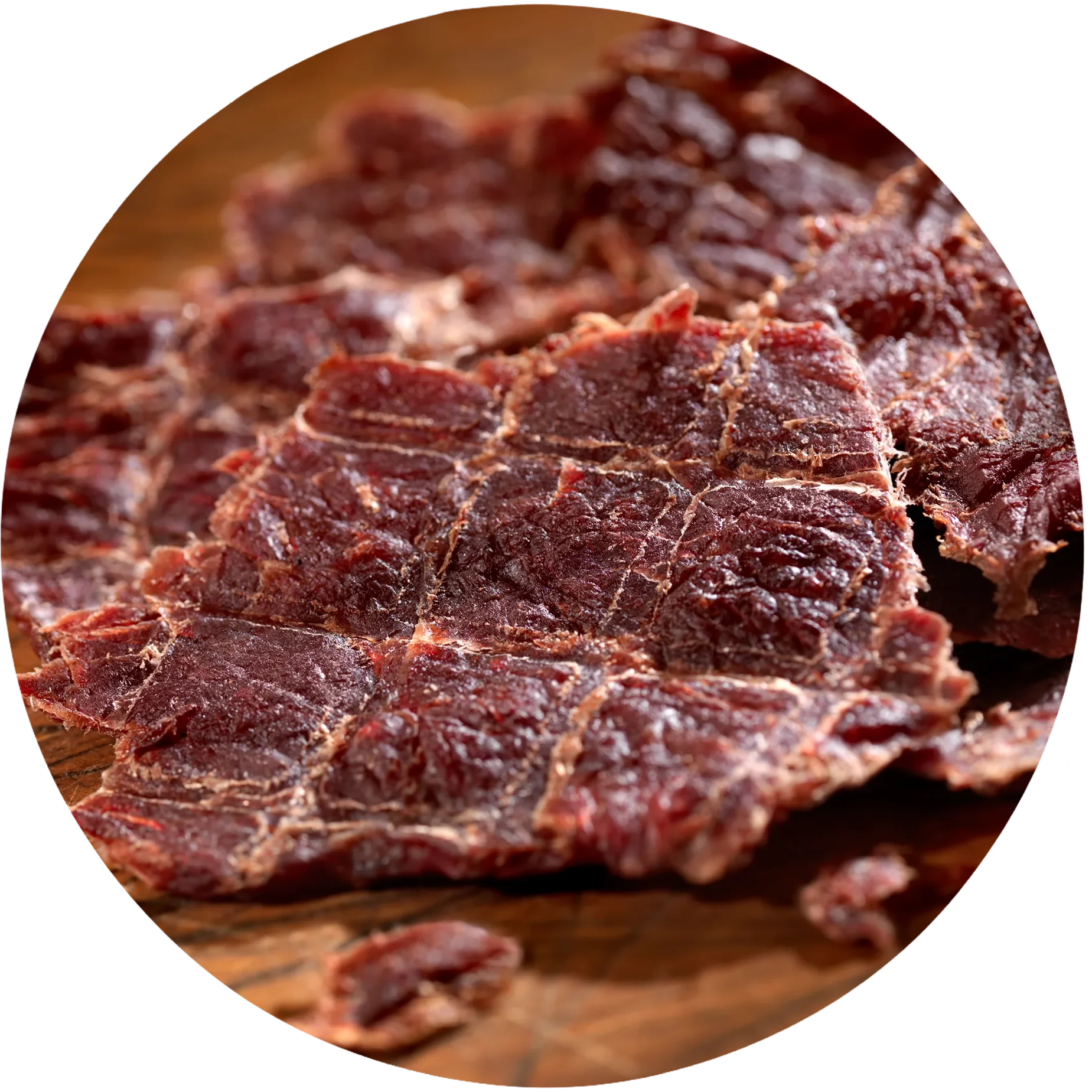 Close-up of pieces of beef jerky on a wooden surface, showing texture and color variation.